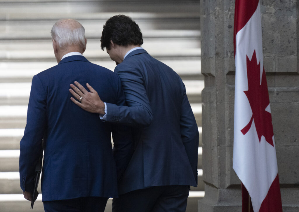 Prime Minister Justin Trudeau puts his hand on United States President Joe Biden