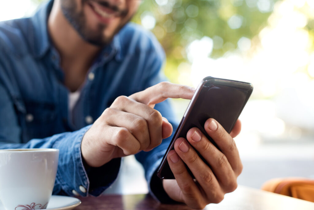 Outdoor portrait of modern young man with mobile phone in the street.