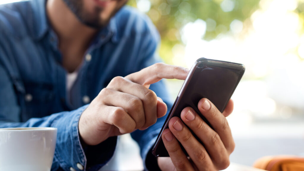 Outdoor portrait of modern young man with mobile phone in the street.